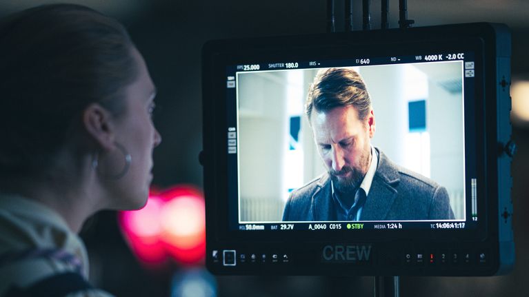 An employee in front of a screen showing a male actor.