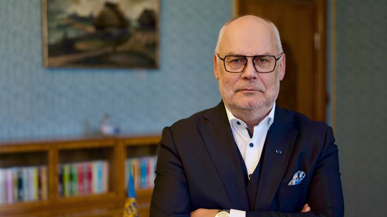 Silmälasipäinen harmaantunut mies puvussa istuu Viron presidentinlinnan neuvotteluhuoneessa.