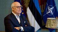 Silmälasipäinen harmaantunut mies puvussa seisoo Viron presidentinlinnan neuvotteluhuoneessa ja katsoo ulos, taustalla EU:n, Viron ja Naton liput.