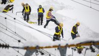 Työntekijät lapioivat lumen peittämiä junaratoja paksun kinoksen alta. 
