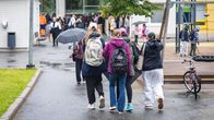 Lapsia kävelee koulun pihalla reput selässä.
