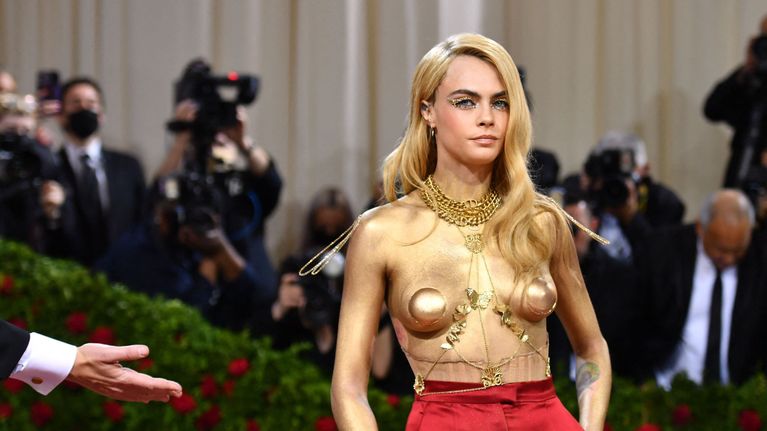 Cara Delevingne punaisissa satiinihousuissan. Yläosan koristeena koruja ja pari kuppia, ei muuta.