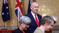 John Healey seisomassa samalla kun hänen etualallaan on kaksi henkilöä.