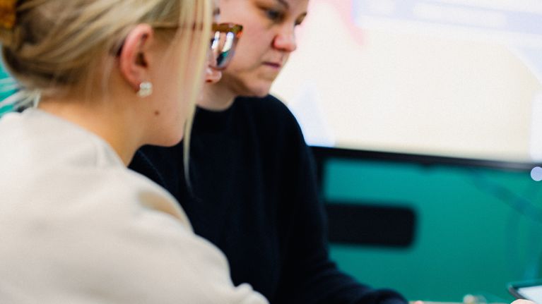 Two Yle employees working together at a computer.