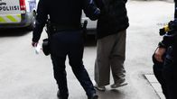 Police officer seen escorting a young man towards a police vehicle.