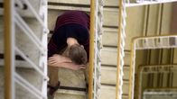 A teenager sitting on a flight of stairs, shot from above.