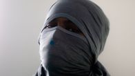 Vanki on käärinyt huivin kasvojensa suojaksi, vain silmät näkyvät.