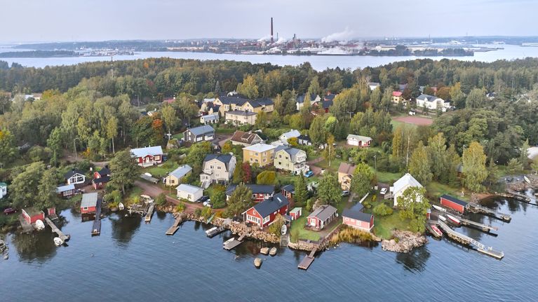 Aerial view of a seaside urban area with houses in the foreground and a smokestack in the distance.