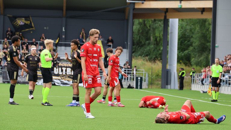 Två Jarospelare ligger på gräset, samtidigt som SJK-spelare talar med domaren.
