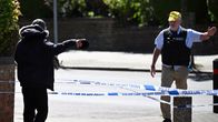 Kaksi henkilöä keskustelee poliisin eristysnauhan luona.