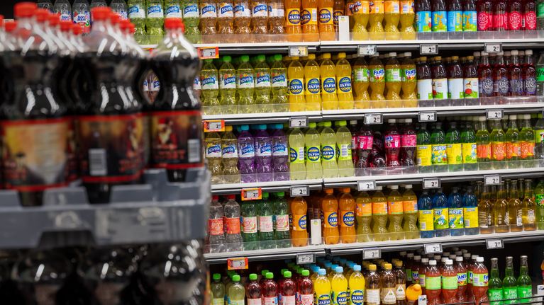 Grocery shop shelves full of soft drink bottles.