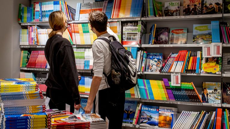 Asiakkaita tutkimassa oppikirjoja Suomalaisessa Kirjakaupassa Helsingissä
