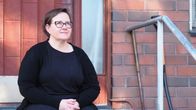 Nainen istuu etuovelle vievillä portailla.