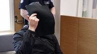 Syytetty peittää kasvojaan oikeussalissa.