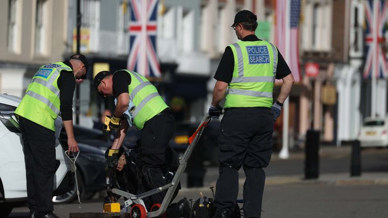 Poliisit tekemäsä turvavalmisteluja kadulla Lontoossa. Taustalla Britannian ja Yhdysvaltojen lippuja.