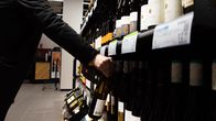 Asiakas viinihyllyn luona Alkossa.