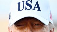 Lähikuvassa USA-lippalakkiin pukeutunut Donald Trump.