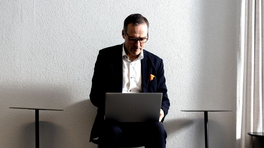 Mikko Kautto työskentelee läppärillä toimiston käytävällä tuolilla istuen.
