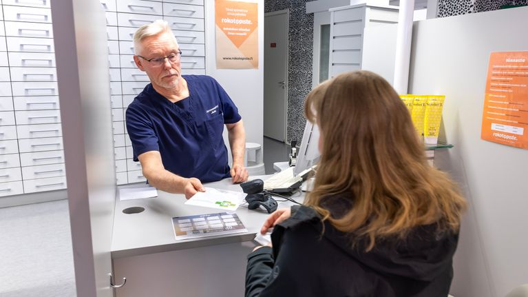 Farmaseutti ojentaa lääkelaskun asiakkaalle.