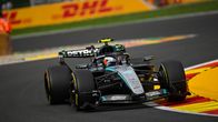 Formula 1 -auto ajaa kilparadalla, taustalla näkyy keltaisia DHL-mainoksia ja useita ihmisiä.