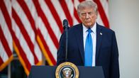 Donald Trump seisoo puhujakorokkeen vieressä, taustalla Yhdysvaltojen lippuja. Korokkeessa on Yhdysvaltain presidentin vaakuna.