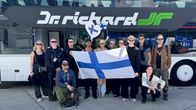 Ryhmä ihmisiä ja he pitelevät käsissään Suomen lippua.