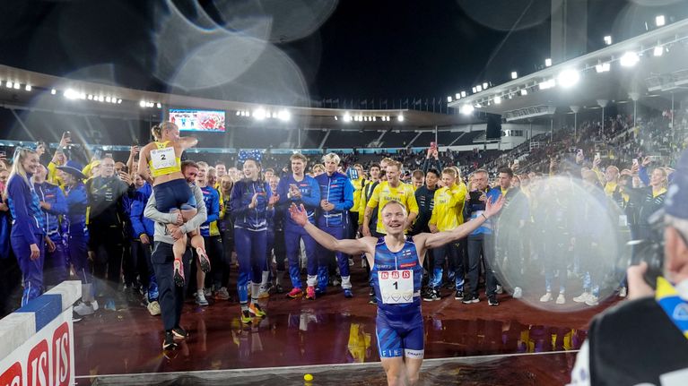 Joonas Rinne tuulettaa seisoen vesieteessä. Ympärillä runsaslukuisesti Suomen ja Ruotsin urheilijoita.