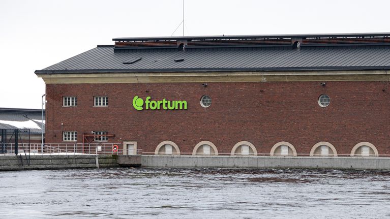 Punatiilinen rakennus veden äärellä, jossa on Fortumin vihreä logo.