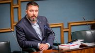 En man i blå kavaj med gråsprängt skägg sitter i riksdagens plenisal.