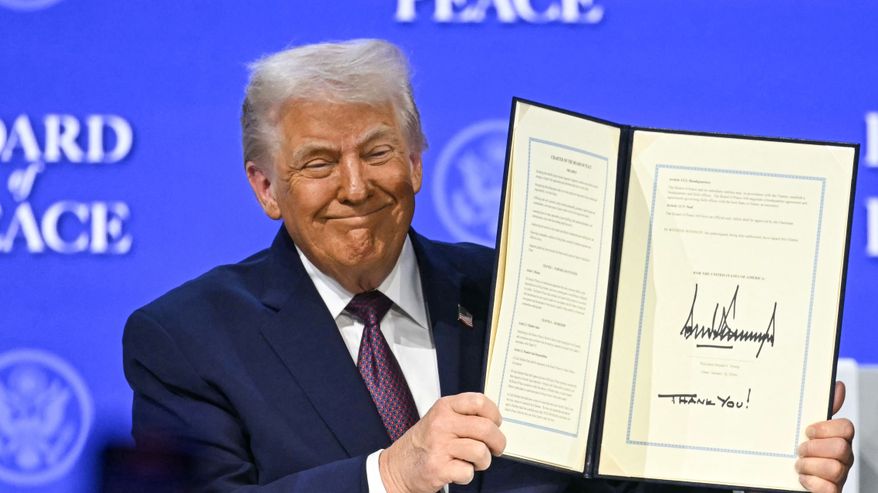 Donald Trump näyttää kädessään avoinna olevaa sopimusta, jossa on hänen allekirjoituksensa.