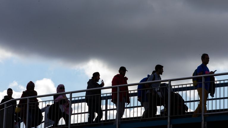 Photo shows migrants crossing a bridge.