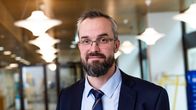 Ville-Veikko Ahonen liiketilassa pukeutuneena siistiin pukuun ja solmioon. 