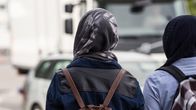 Unga kvinnor med huvudduk i stadsmiljö, sedda bakifrån.
