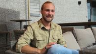 En ung man sitter vid en uteservering i Hangö. Han ser mot kameran och ler.