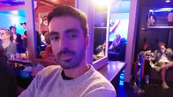 Nuori miesi poseeraa kameralle baarissa.