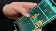 Closeup of two hands holding a smartphone which is showing an electricity price graph.