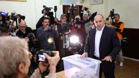 Rumen Radev äänestyspaikalla äänestyslaatikon edessä ison kuvaajaryhmän kuvatessa häntä samalla.