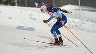 Skidskytt i blå tävlingsdräkt i uppförsbacke.
