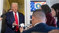 Donald Trump puhuu median edustajille lentokoneen matkustamossa.