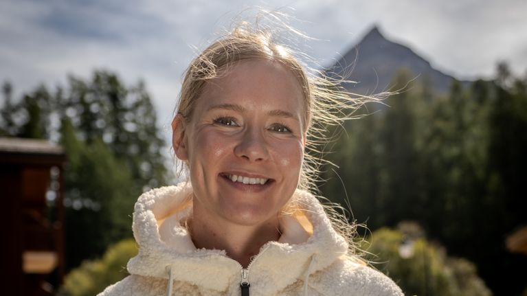 Suvi Minkkinen i solskenet i Frankrike med en bergstopp i bakgrunden.