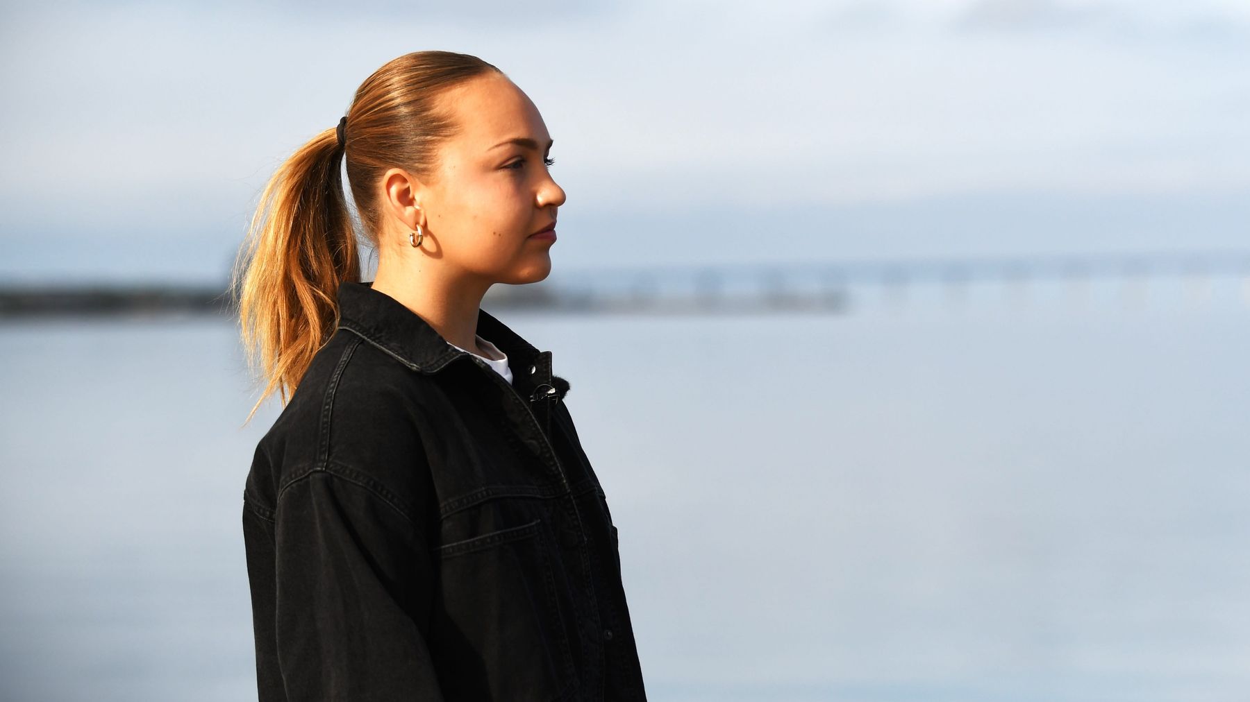Oona Sevenius tittar ut mot havet i Malmö, med bron till Danmark i bakgrunden.