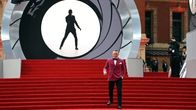  Daniel Craig poseeraa punaisella matolla peitetyillä portailla.