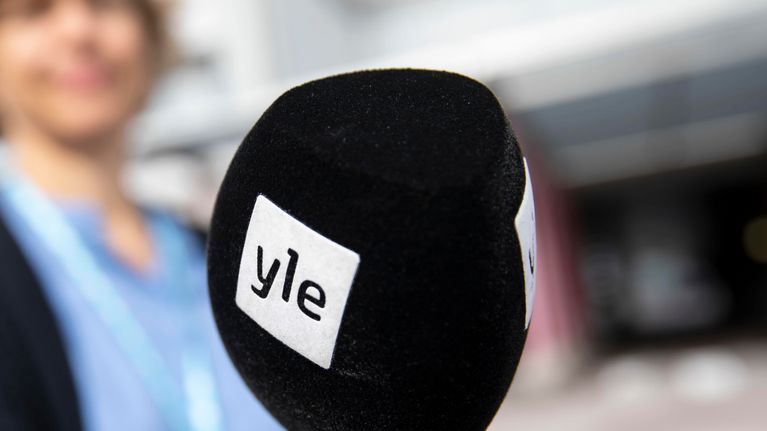 Käsi pitelee Ylen mikrofonia.