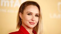 Hayden Panettiere katsoo kameraan punaisessa takissa. Taustalla näkyy keltainen seinä.