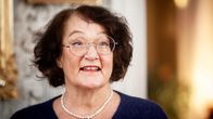 En kvinna, Monika Fagerholm, i blå tröja och pärlhalsband tittar leende förbi kameran.
