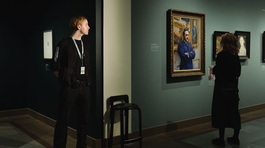 Museovalvoja seuraa vahtipaikaltaan naista, joka katsoo maalausta. Laaja kuva.