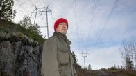 Punapipoinen mies seisoo suurten sähkölinjojen alla.