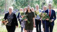 Erna Solberg ja muista muistojuhlaan osallistuneita kukkakimput kädessään.