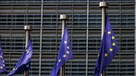 Kolme Euroopan unionin lippua liehuu lipputangoissa nykyaikaisen rakennuksen edessä.