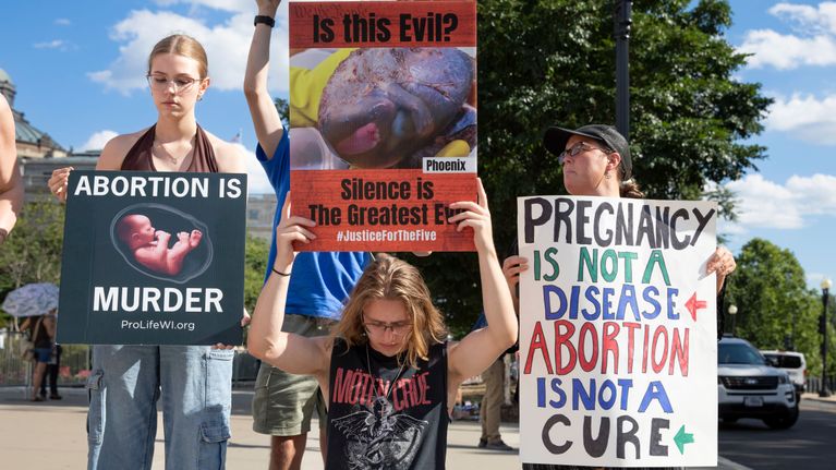 Demonstranter håller upp skyltar mot abort.